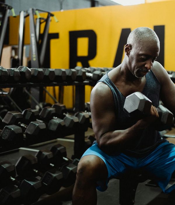 Man performing a controlled dumbbell exercise in a dark, focused environment.